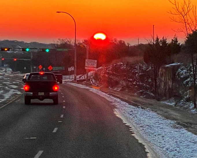 orange sunrise on snowy road with truck
